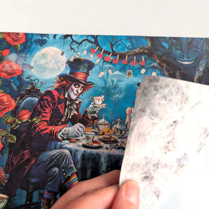 A hand holds a translucent, sheet of rice paper in front of a colorful printed illustration featuring the Mad Hatter from Alice in Wonderland at a tea party under a full moon.