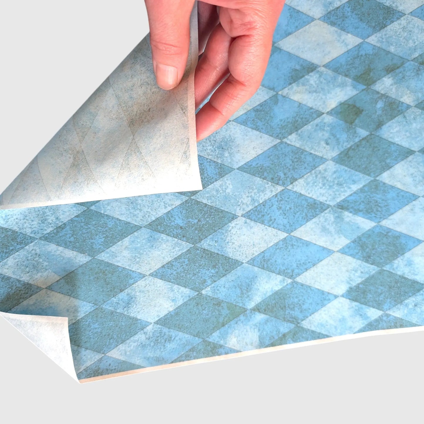 A hand flipping a teal green decoupage paper to show the back of the paper