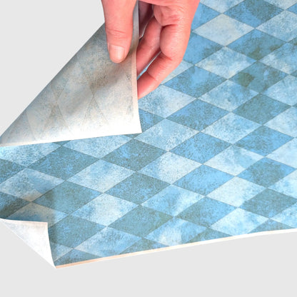 A hand flipping a teal green decoupage paper to show the back of the paper