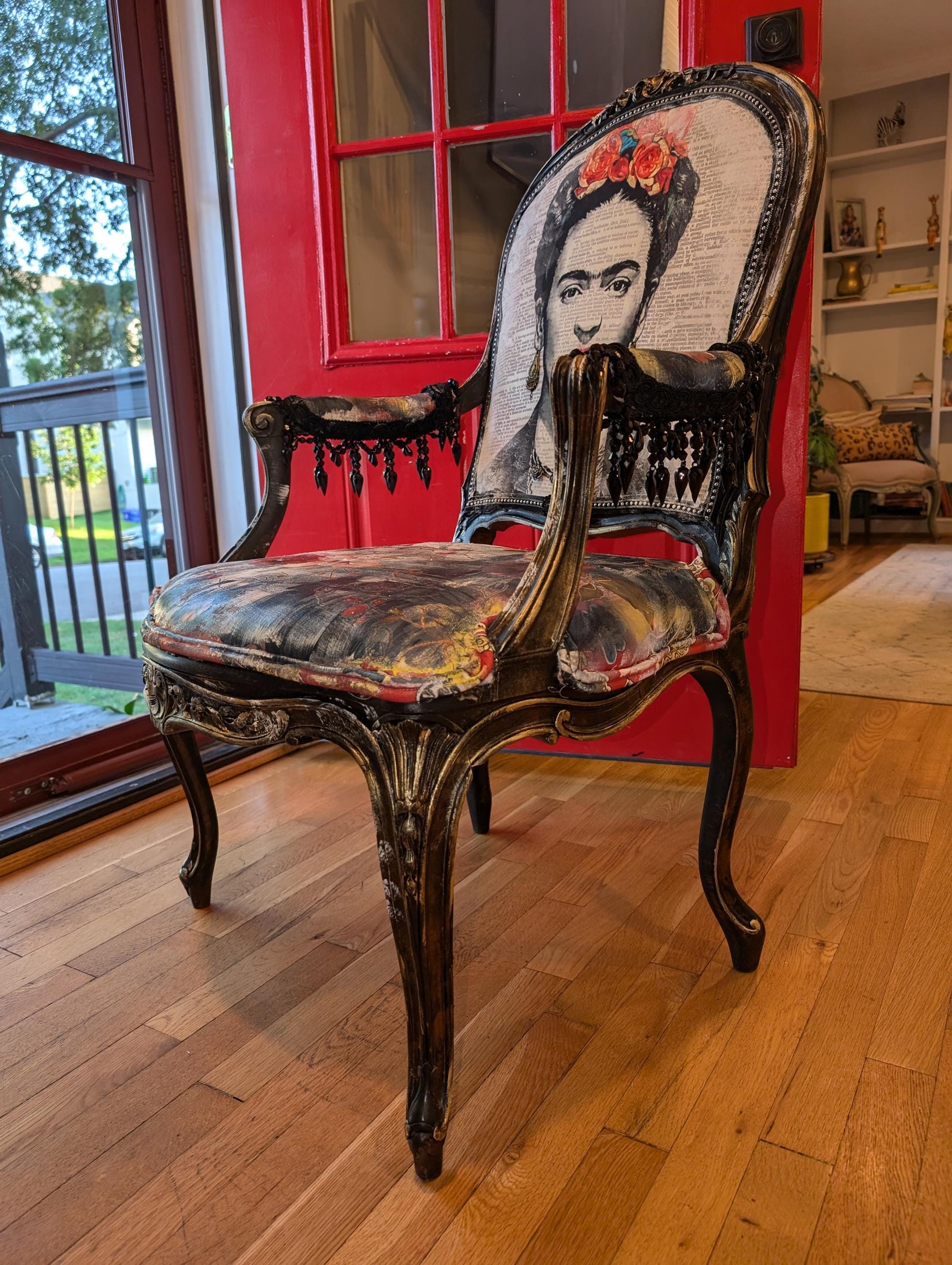Bring style and character to your home decor with this one-of-a-kind Frida Kahlo vintage French upcycled chair. The chair frame is made of solid wood, painted black, and decorated with gold wax. Chair decsorated with extar large black tassels.
