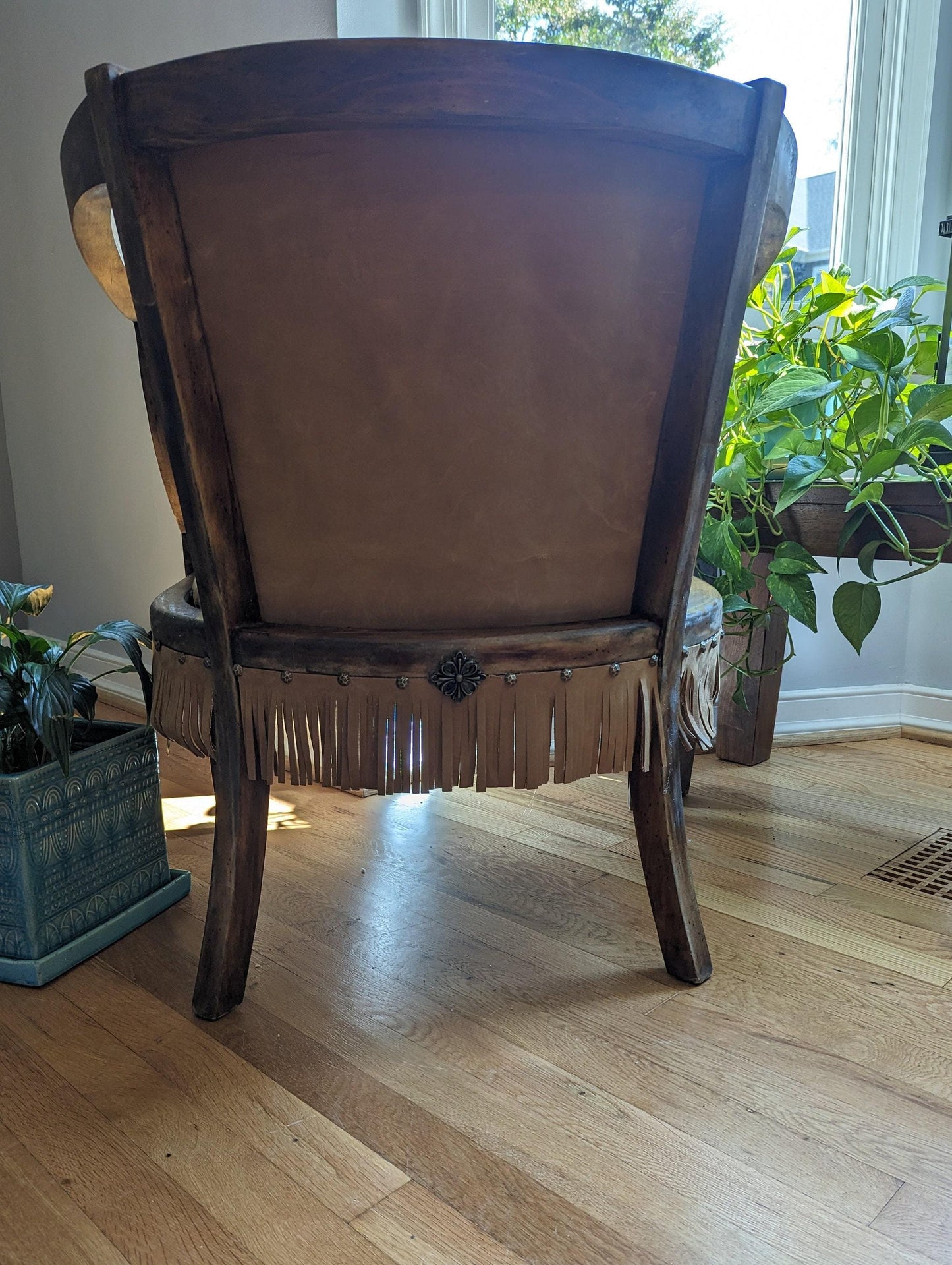 Western-style leather chair. Upholstry done with Cow hide.  One of a kind solid wood chair. Decorated with  nail heads and leather fringe. This chair will bring a unique American  patriotic style to any space.
