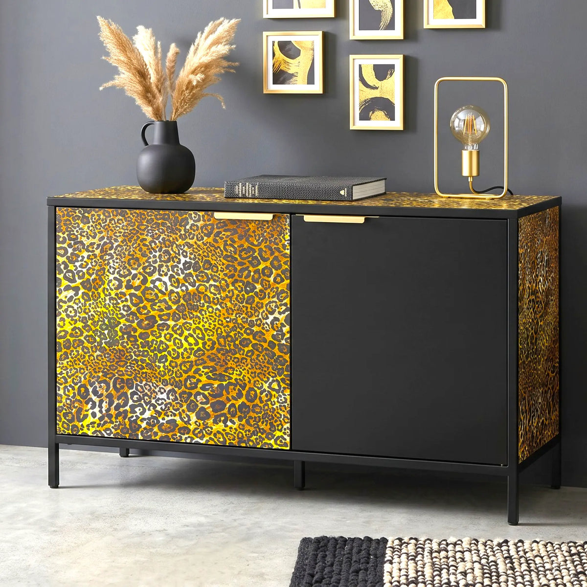 A modern sideboard cabinet with a black frame and doors featuring a bold yellow, gold, and brown leopard print pattern, styled in a contemporary room setting.