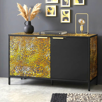 A modern sideboard cabinet with a black frame and doors featuring a bold yellow, gold, and brown leopard print pattern, styled in a contemporary room setting.
