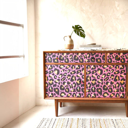 Pieces Reclaimed pink leopard print decoupage paper applied to a mid-century modern wooden sideboard cabinet