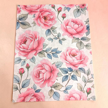 Pink roses tissue paper  with a watercolor-style pink rose pattern on a light background, laid flat on a soft peach-pink surface.