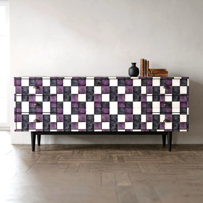 A mid-century modern sideboard with a checkerboard pattern of purple, black, and white textured tiles, set against a minimalist light gray wall and dark wood parquet floor.